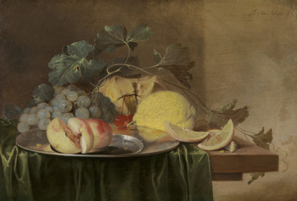 Still life on a wooden table partly covered with a dark green cloth with a peach, grapes, cherries and lemon